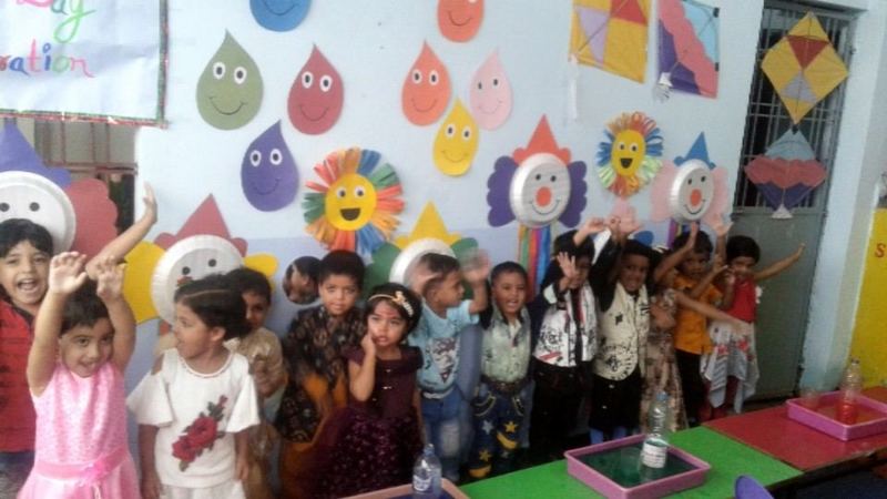 Nursery children with their classroom craft wall